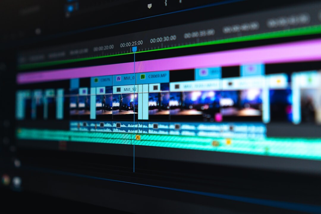Video editor working at computer with multiple screens showing editing software